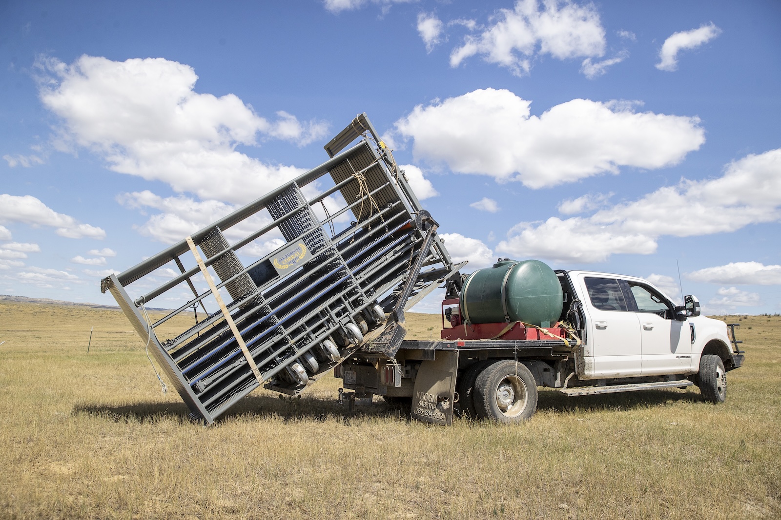 A bale bed pickup unloads the All-Purpose Corral in the pasture.>>